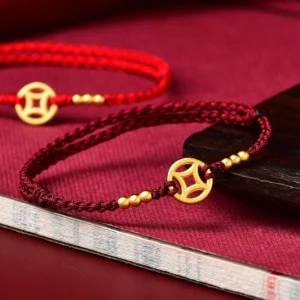 Red string copper coin braided bracelet with gold beads on velvet background