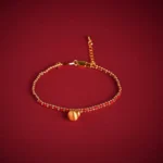 Red string copper brass gourd bracelet with adjustable tail chain and gold beads on dark background