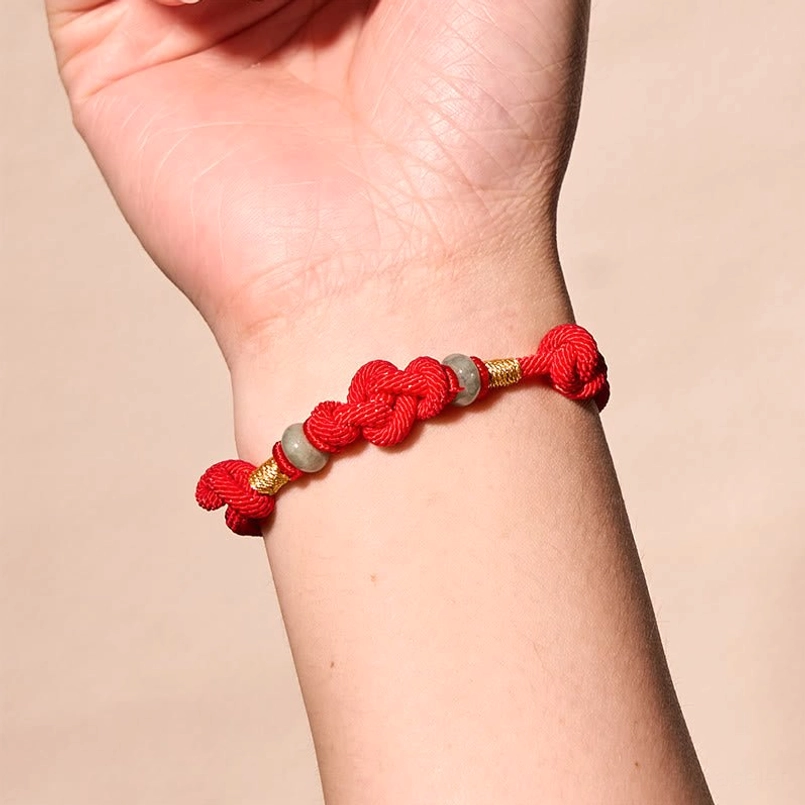 Red string couple bracelet fitted on wrist showing braided design