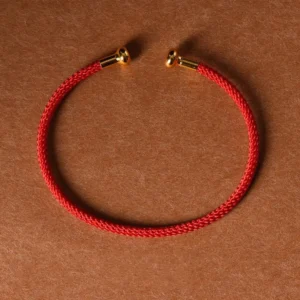 Red braided open cuff bracelet with gold metal end caps, top-down flat lay view on craft paper