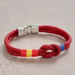 Red woven double wrap braided rope knot strength bracelet with silver clasp on stone background