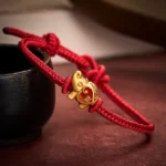Red string elephant charm bracelet with adjustable knot detail, shown on dark tabletop