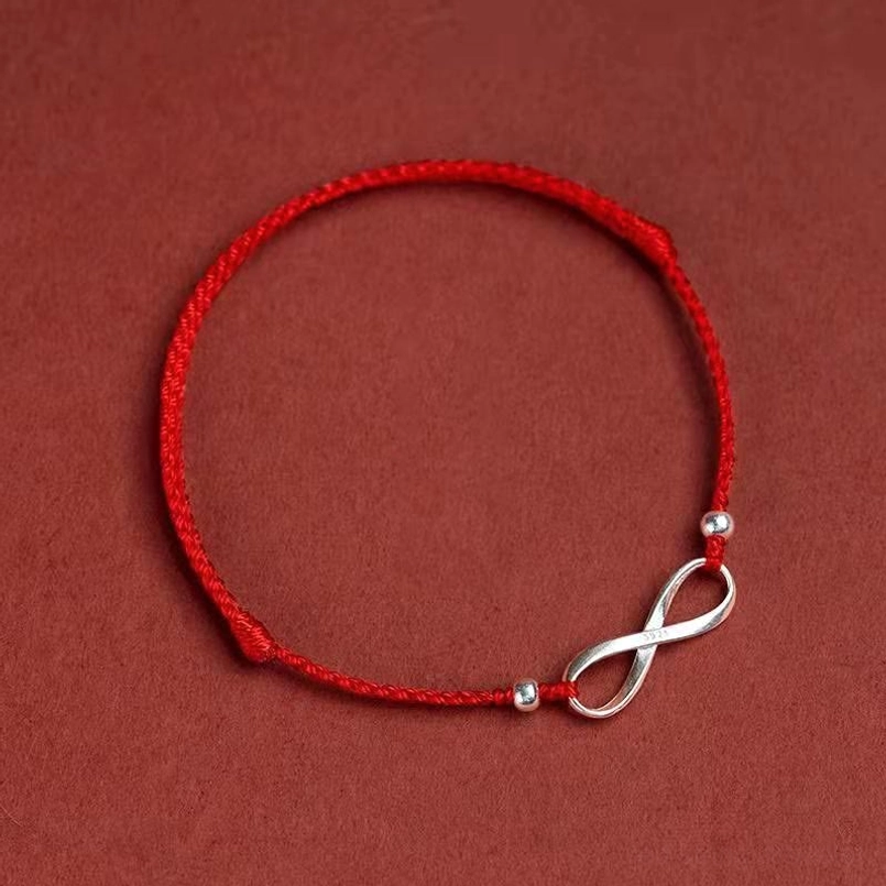 Single red cord endless knot bracelet with sterling silver beads overhead view