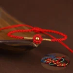 Red flower gold bead handmade protection bracelet close-up on wooden tray