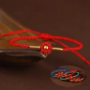 Red flower gold bead handmade protection bracelet close-up on wooden tray