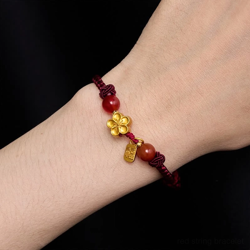 Red string fu charm bracelet worn on human wrist close up shot