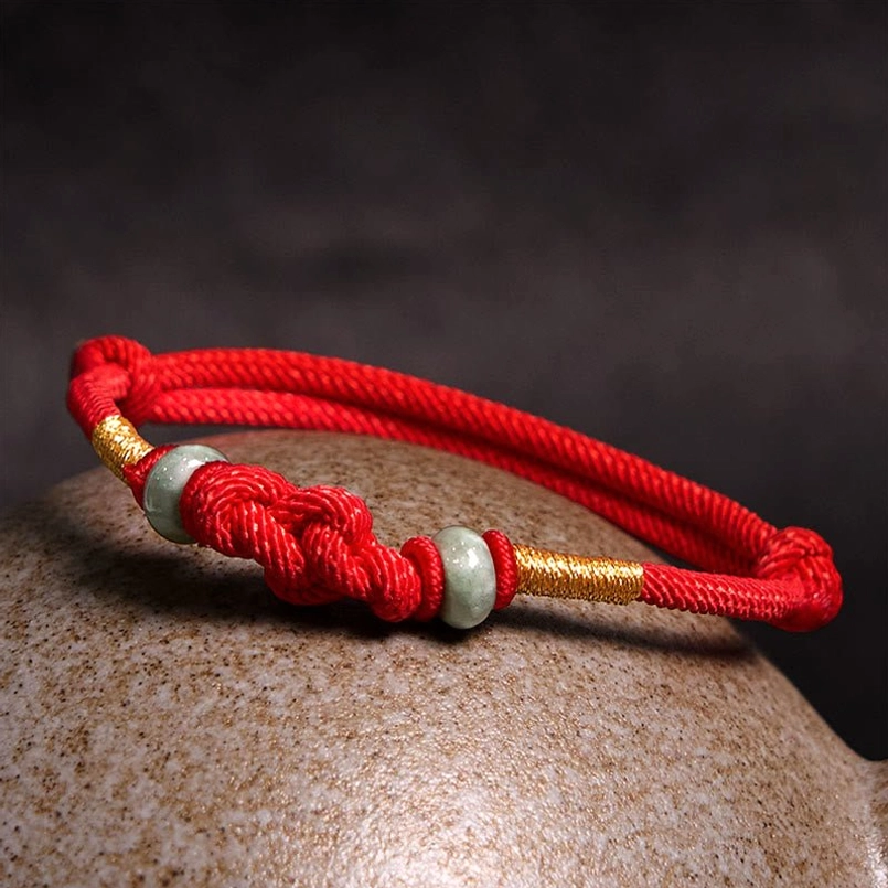 Side view of red string fortune knot bracelet on stone surface