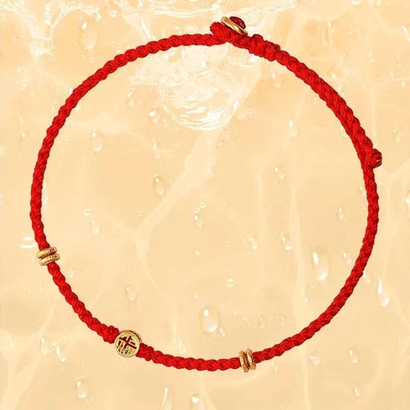 Red string Fu charm bracelet on water drop textured light background