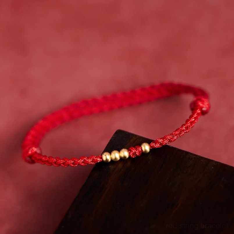 Red string gold bead bracelet adjustable knot close up high angle view