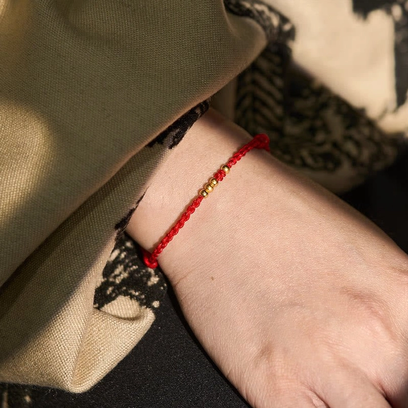 Red string gold bead bracelet worn on wrist daily casual side view