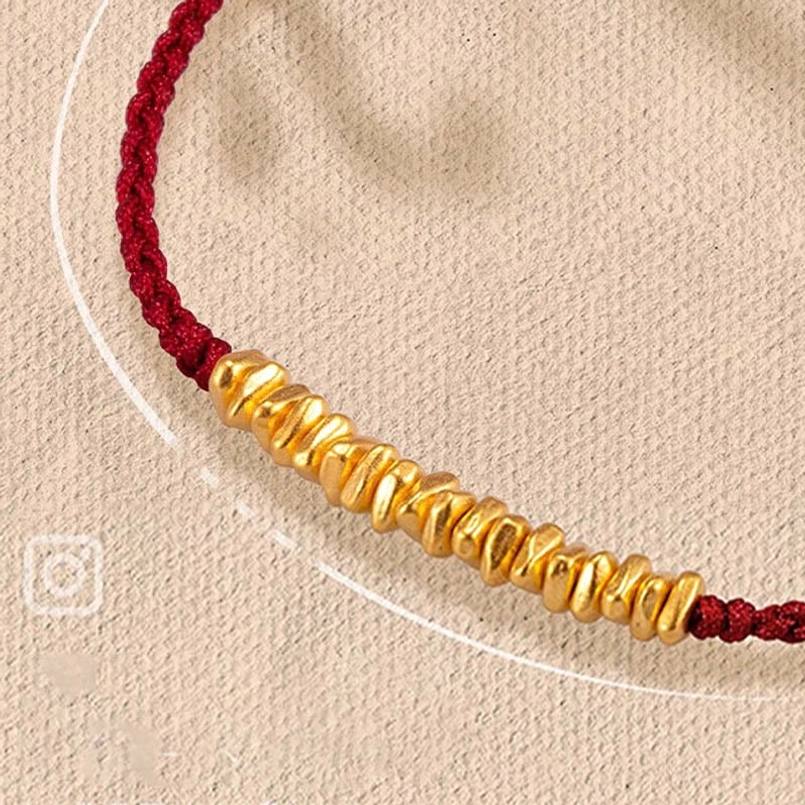 red string bracelet with sequential 999 gold beads on linen background