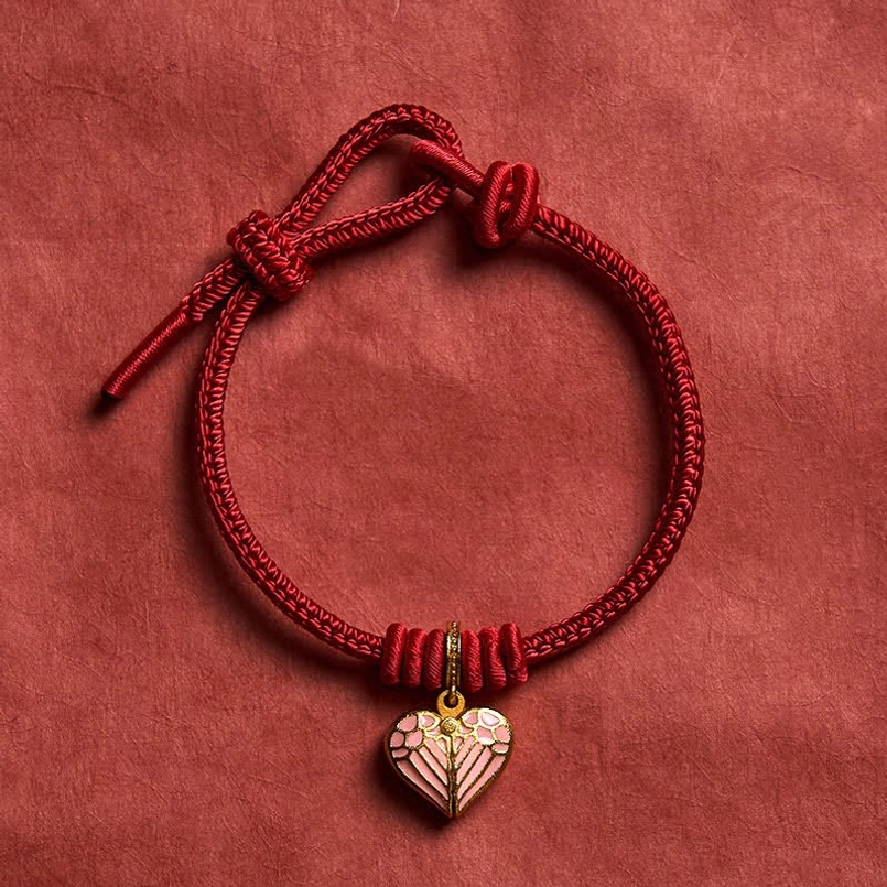 Front view of handmade red string bracelet with pink enamel heart charm and sliding knot closure