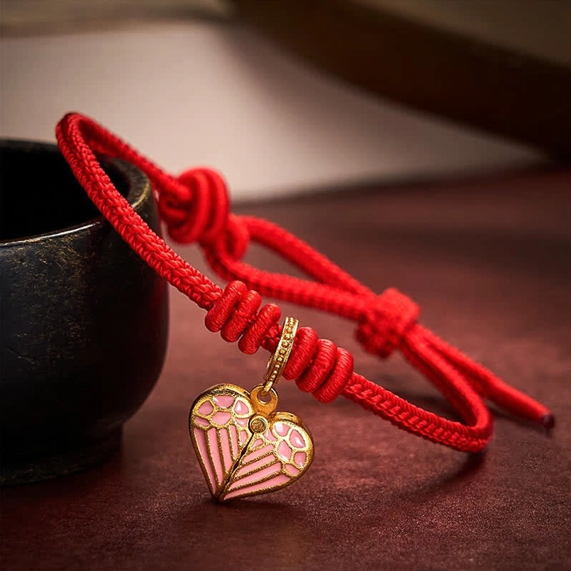 Adjustable red cord bracelet with pink enamel heart charm and gold-tone hardware