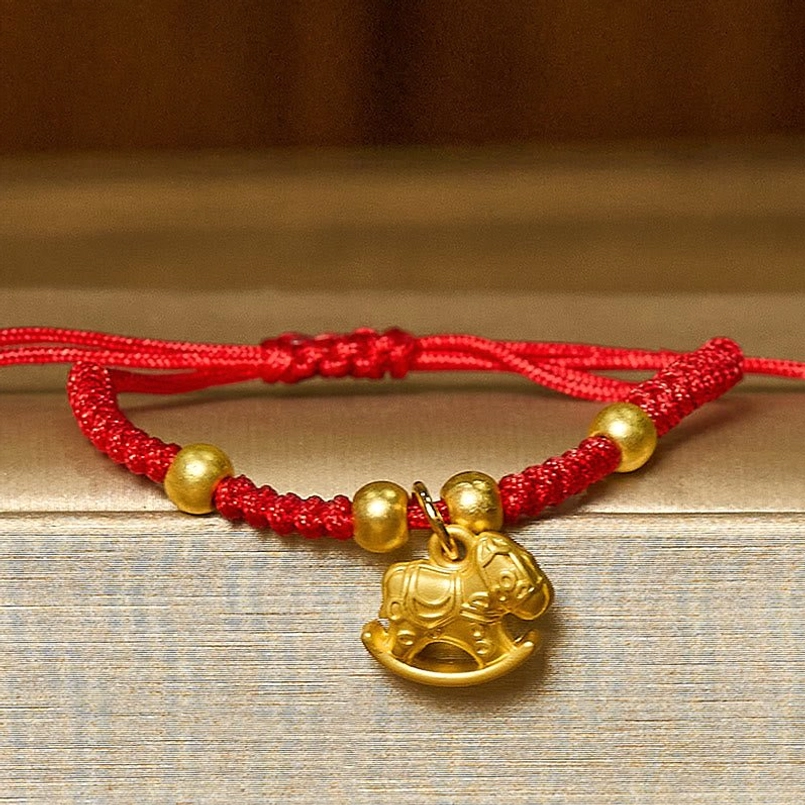 Handmade red braided horse charm bracelet with round gold beads and simple knitted knots, flat lay view