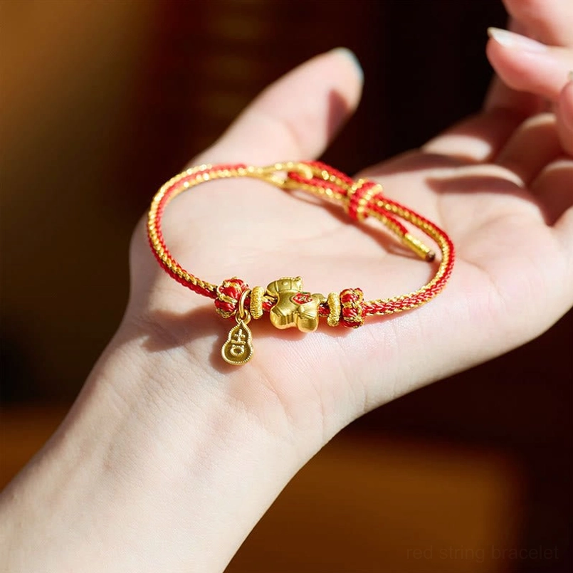 Handcrafted red string horse bracelet held in palm displaying braided rope and metal charms