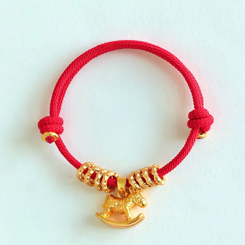 Adjustable knotted red string horse charm bracelet on pure white background top view