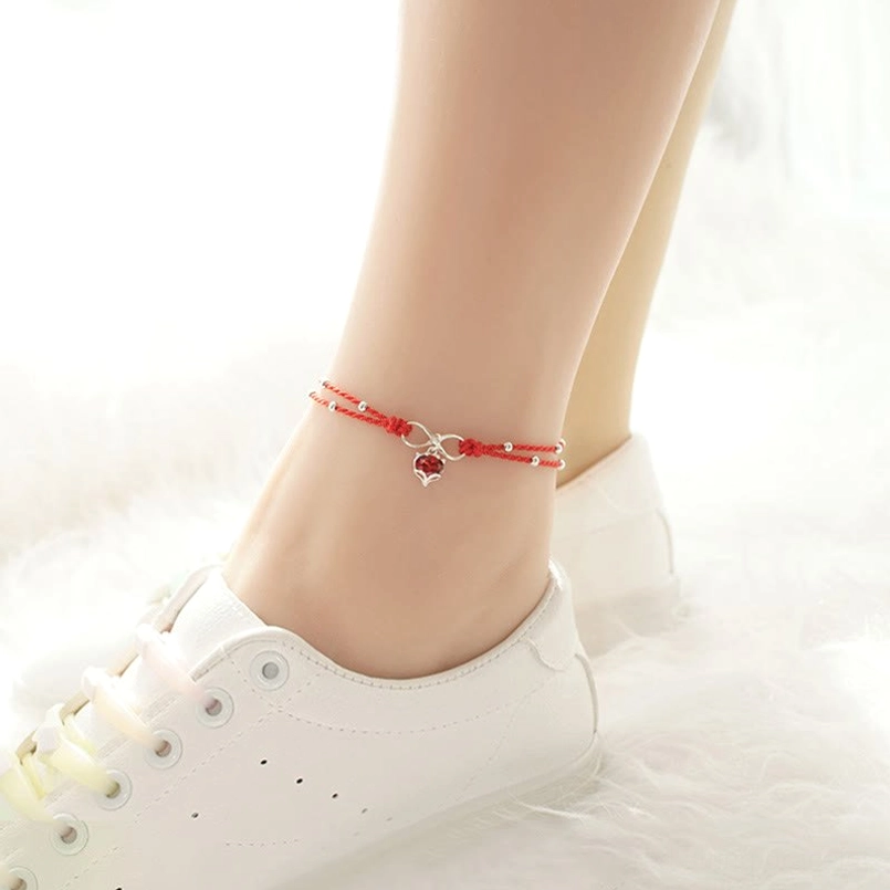 Double-layered red braided anklet worn on ankle with white sneaker and heart charm, on-body lifestyle photo