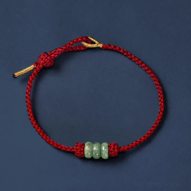 Red string jade bracelet flat lay overhead view on dark blue background