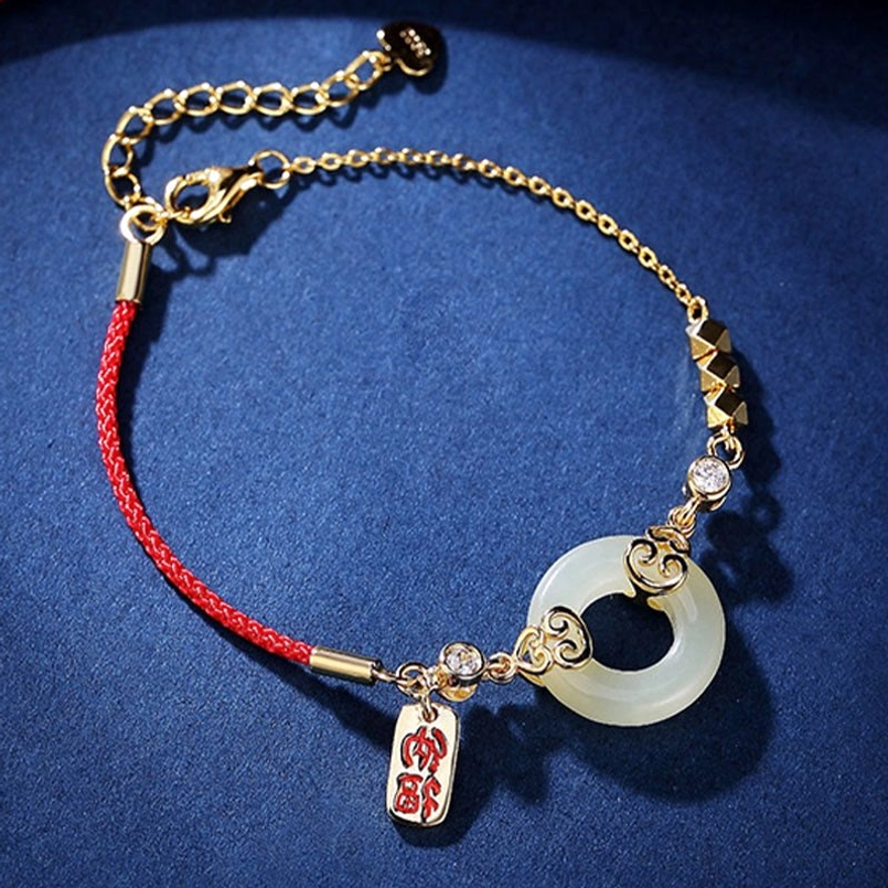 Red string jade peace buckle bracelet flat lay showing gold-toned beads and fortune pendant
