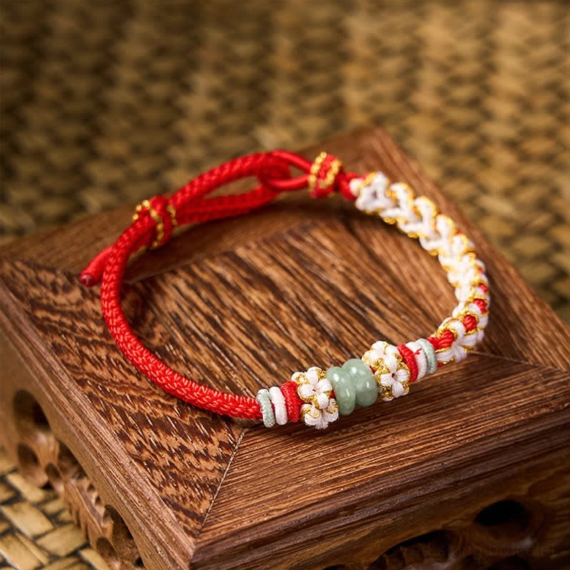 Handmade Chinese knot luck bracelet with jade beads on woven mat background