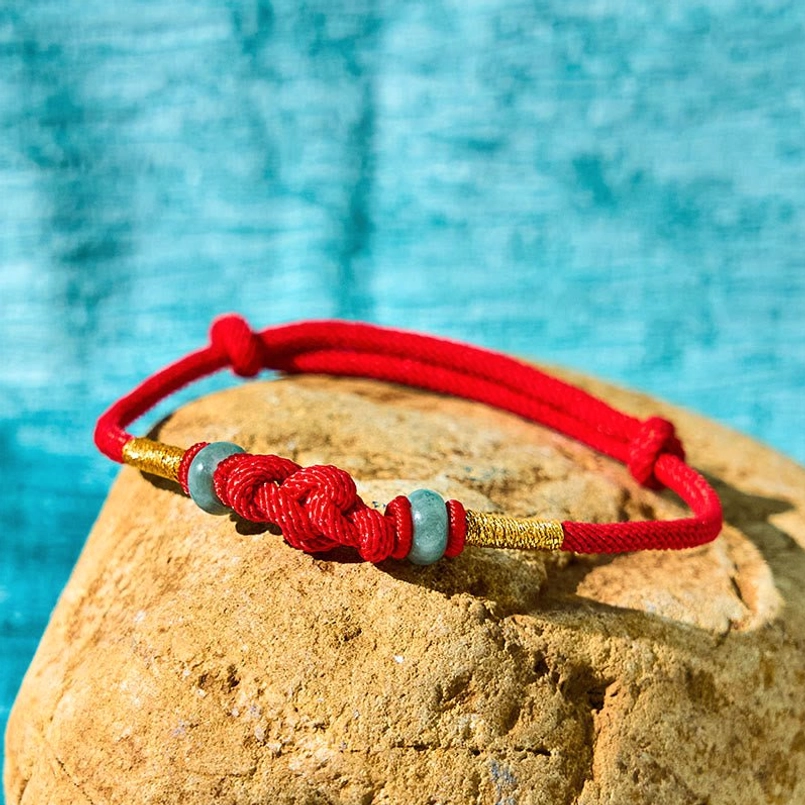 Side view of red string jade bracelet showing braided central knot and adjustable closure