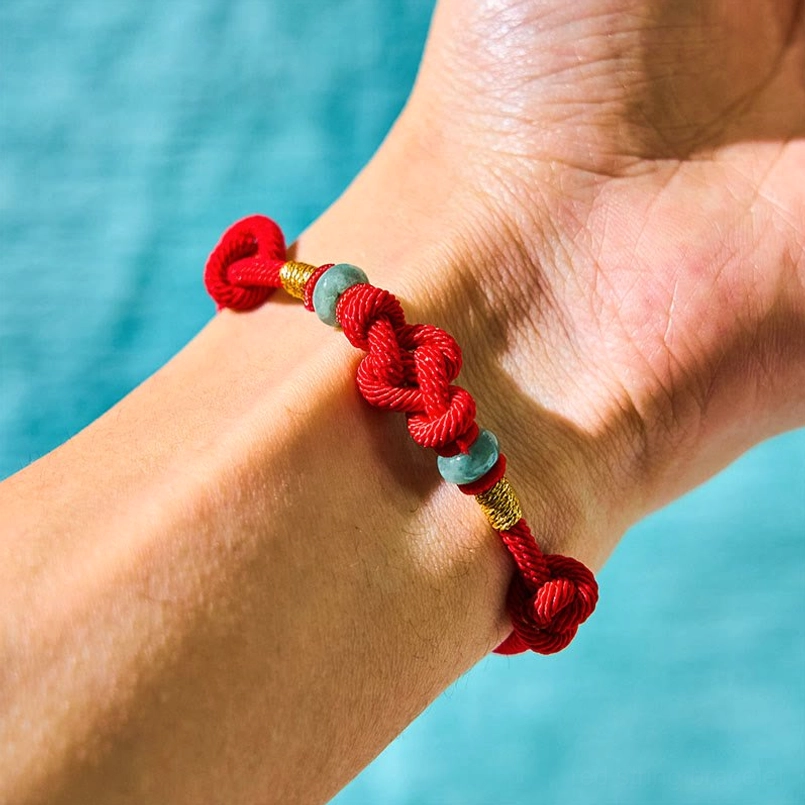 Red string jade couple bracelet worn on wrist with braided knot detail and jade beads
