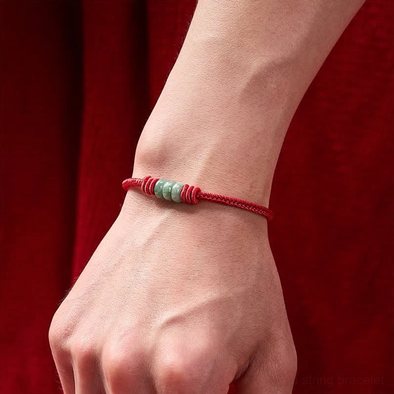 Red string jade protection bracelet worn on wrist showing minimalist adjustable design in real wear