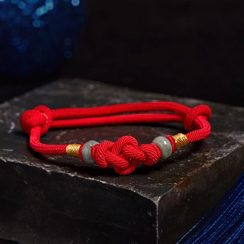 Close-up overhead view of red string fortune knot bracelet with jade beads
