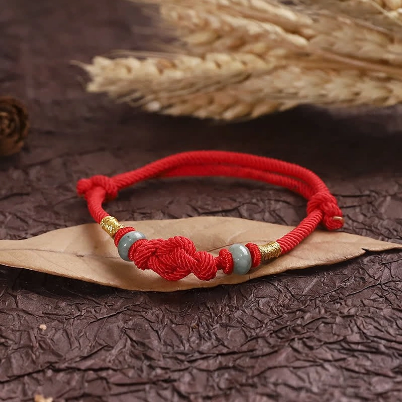 Red string jade fortune knot bracelet flat lay product shot