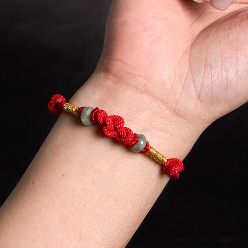 Worn red string jade fortune knot bracelet on wrist