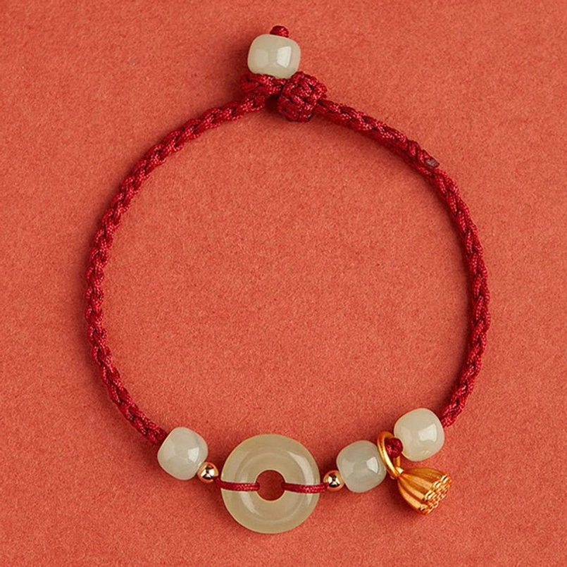 Finished red string jade lotus bracelet flat lay on red background