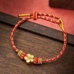 Red string koi fish bracelet with gold charm on wooden background