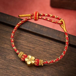 Red string koi fish bracelet with gold charm on wooden background