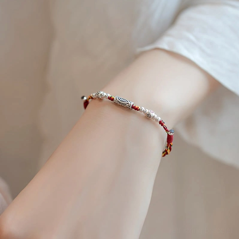 Sterling silver koi charm and beads on red braided cord worn on wrist lifestyle shot