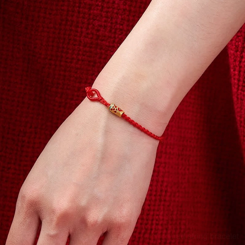 Red string koi fish bracelet worn on adult wrist showing slim fit and charm placement