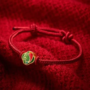 Handmade red string koi fish bracelet with double charm, adjustable sliding knot, flat lay view