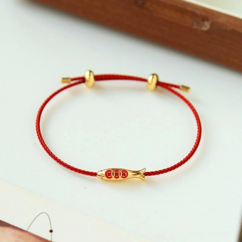 Red braided koi fish prosperity bracelet on wooden table edge