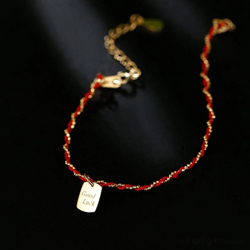 Red string luck bracelet dangling good luck charm pendant side hanging view
