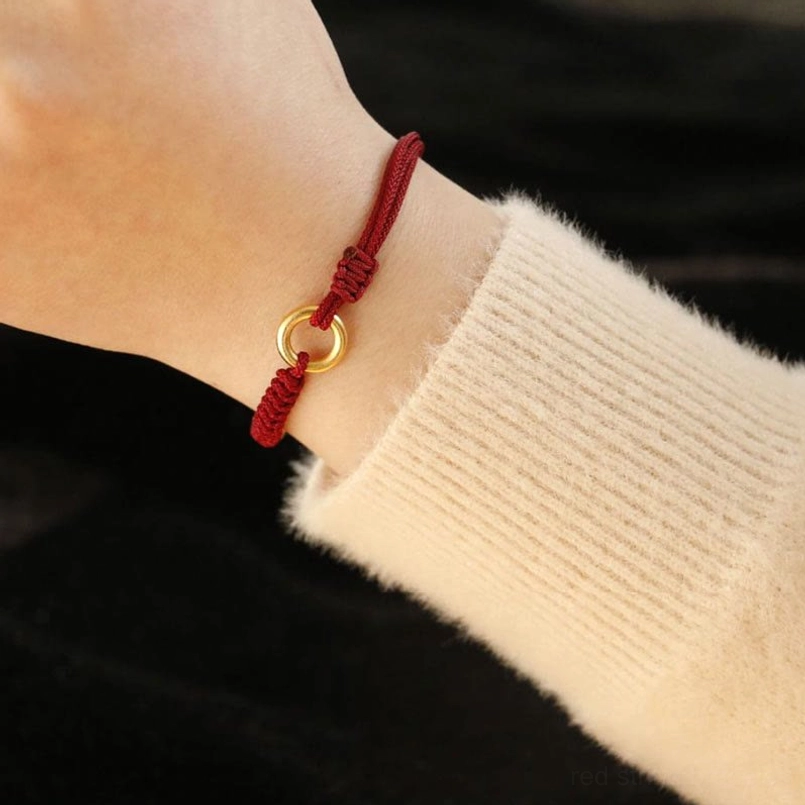 Red String Luck Bracelet Worn On Wrist With Knit Sweater Sleeve
