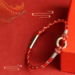 Red string luck bracelet with 925 sterling silver peace buckle on red festive background with gift box