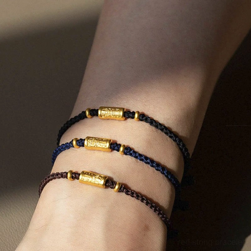Red braided rope bracelet with gold barrel charm - close-up detail shot