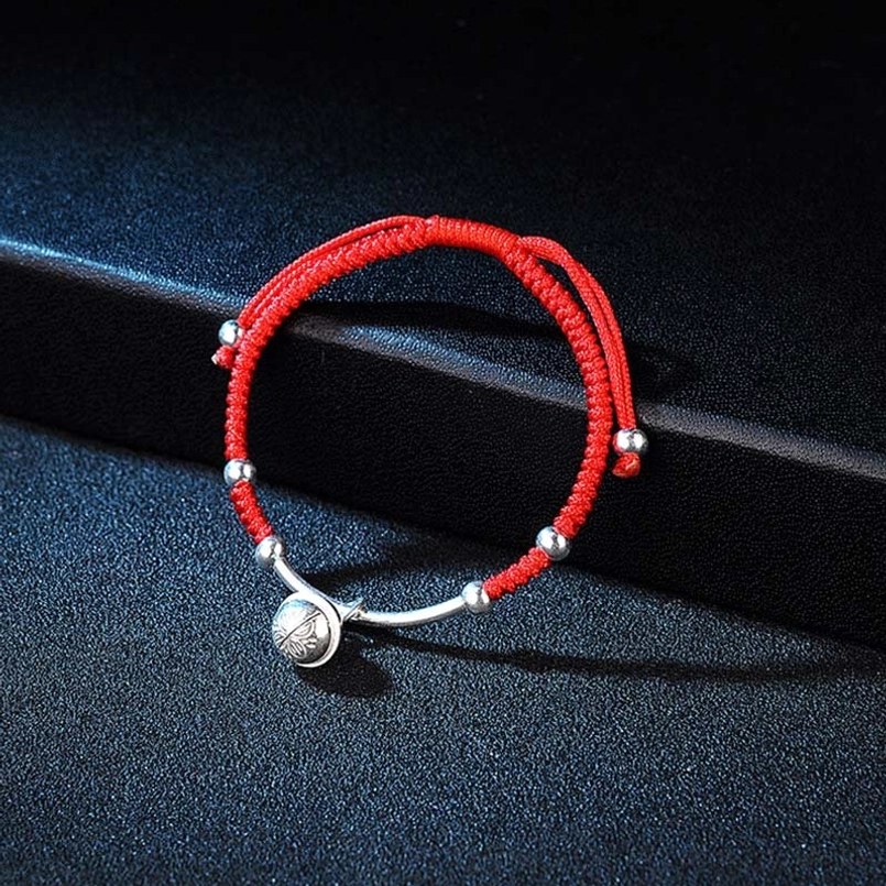 Lucky red string bell bracelet side view showing woven texture and silver beads