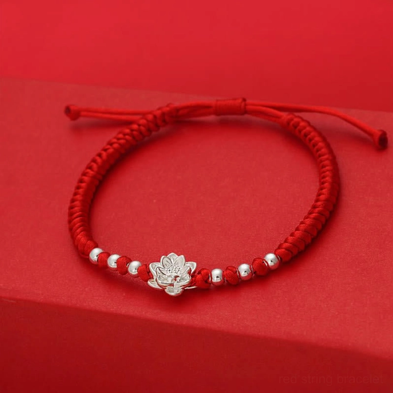 Red string lucky bracelet with 999 silver lotus charm on red display platform