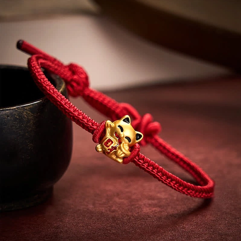 3D view of golden lucky cat charm on adjustable red braided cord bracelet