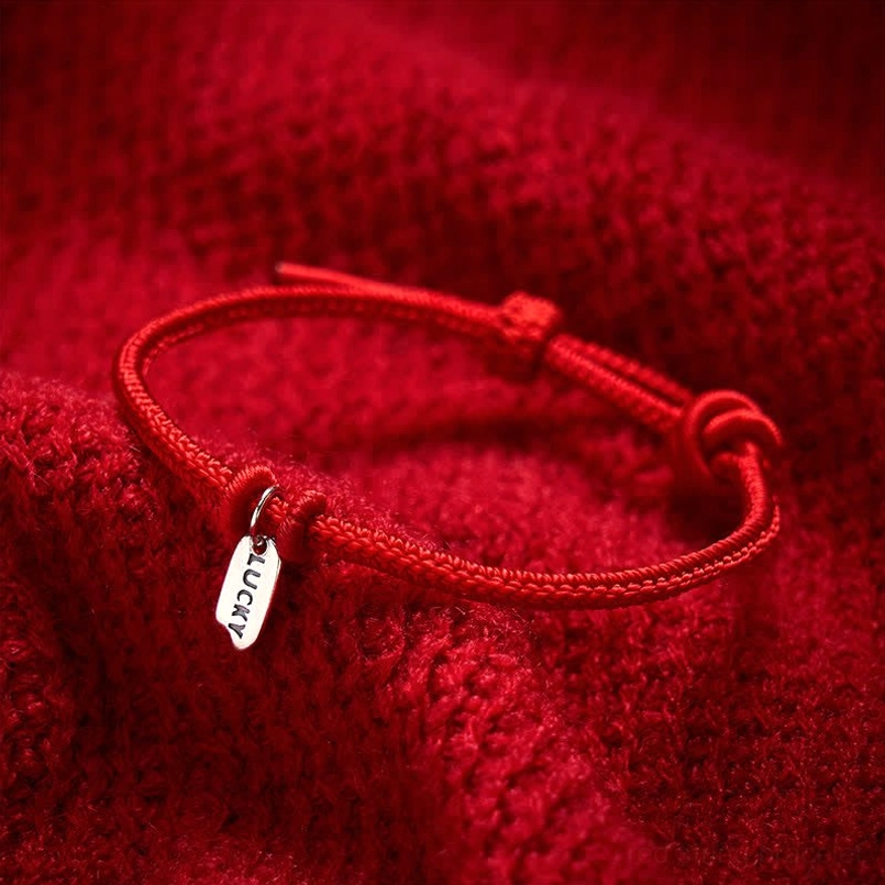 Handmade red lucky bracelet showing sliding adjustable knot on red fabric background