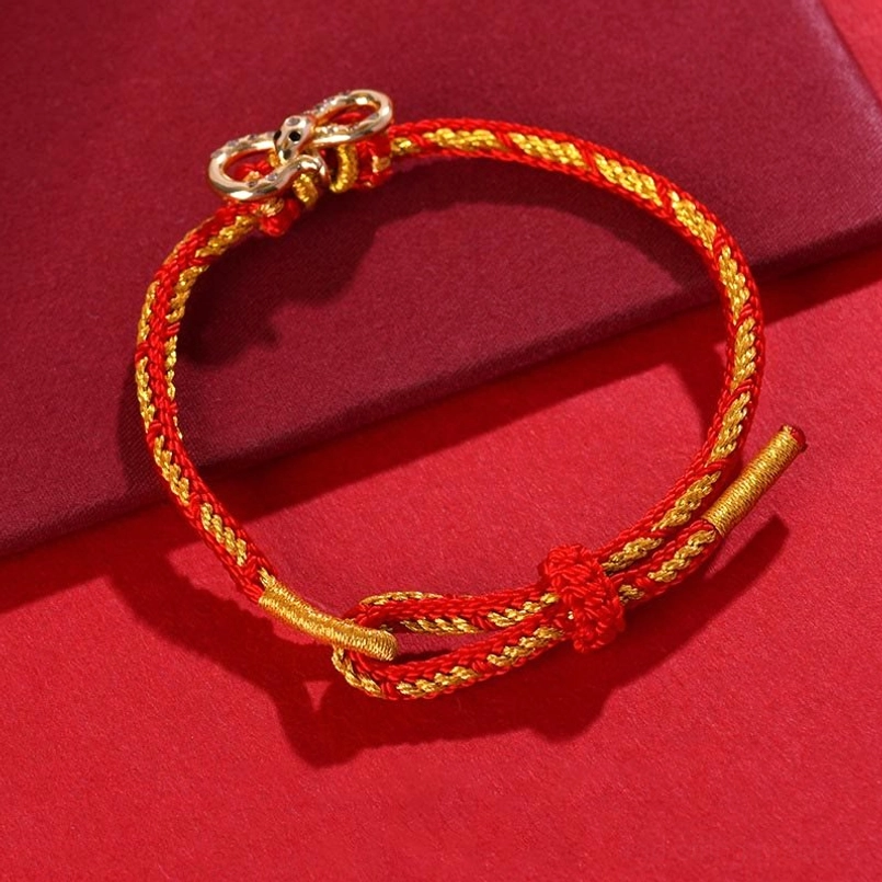 Red String Snake Year bracelet three-quarter view displaying twisted red-gold rope with screw-style metal clasp and decorative knot