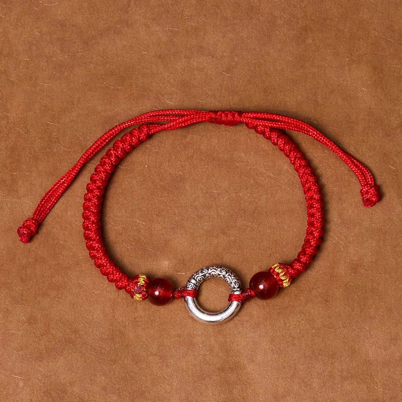 Red braided peace buckle bracelet with dual adjustable pull strings on kraft paper