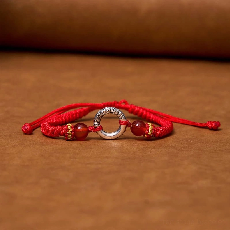 Overhead flat lay of red peace buckle protection bracelet with adjustable sliding knots on wooden background