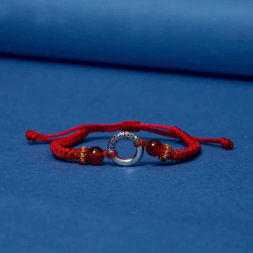 Red string peace buckle bracelet minimalist product photo on studio background