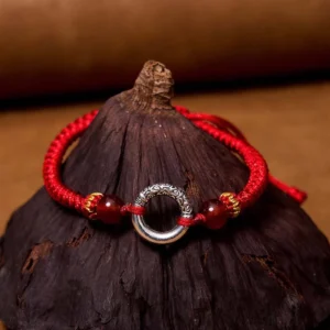Red braided peace buckle bracelet with silver agate beads and adjustable cord on dark wooden surface